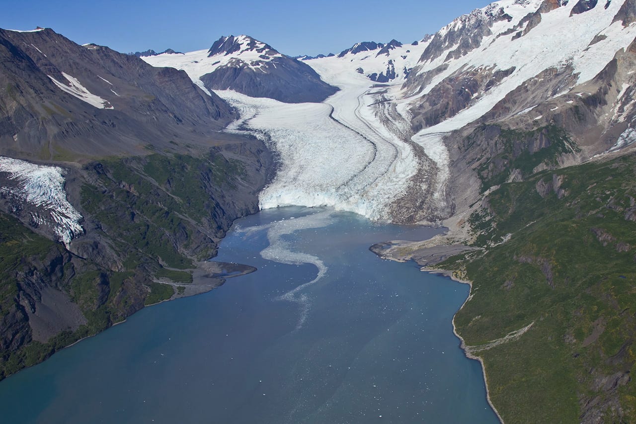 Ice melts in a snaking pattern into an alpine lake