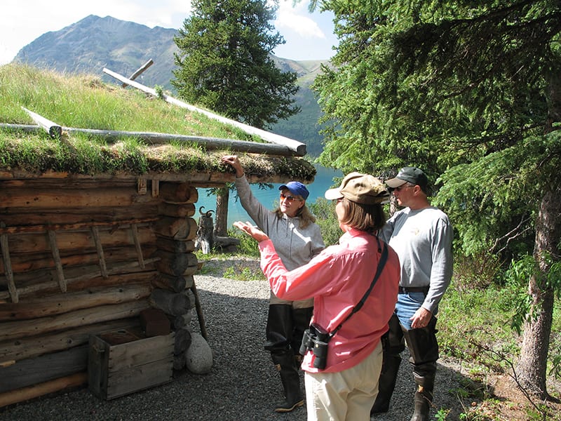 Explorers examine sod roof of Twin Lakes Cabin