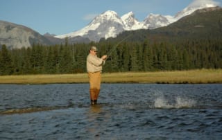 A man battles a fish in a mountain river.