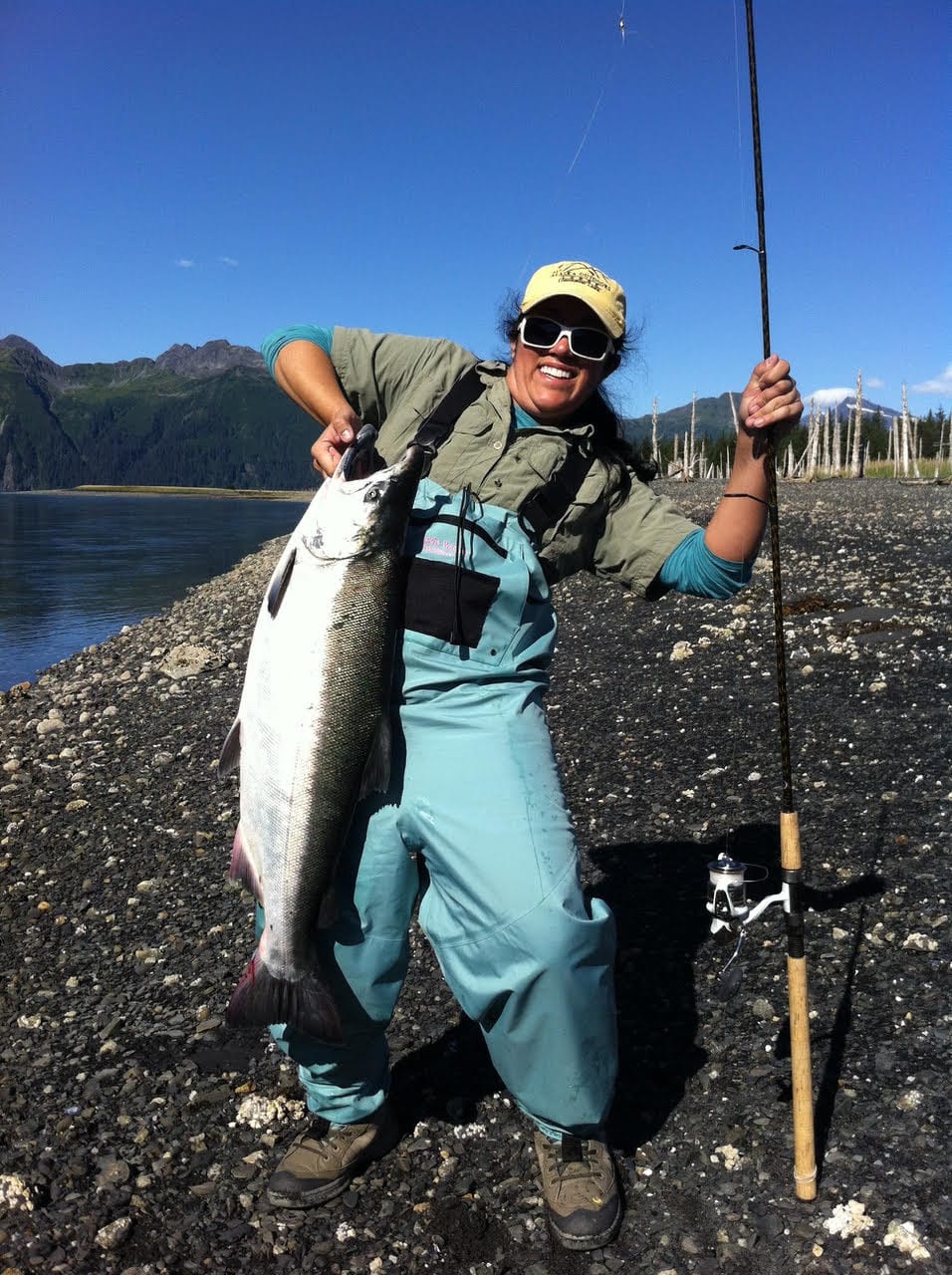 Catching fish this big is sure to put a smile on your face. Angler in waders holding a huge fish and a fishing pole