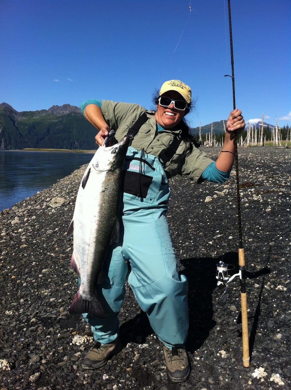 Angler in waders holding a huge fish and a fishing pole