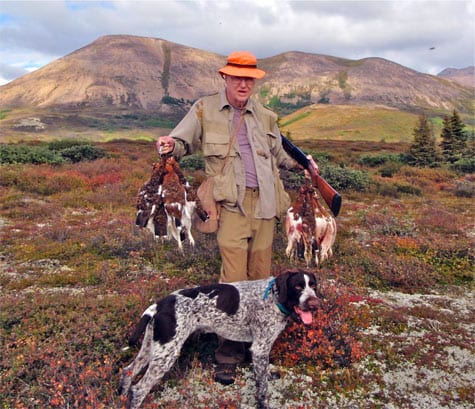 Wing shooting in Alaska is better with us Man and dog after a successful ptarmigan hunt