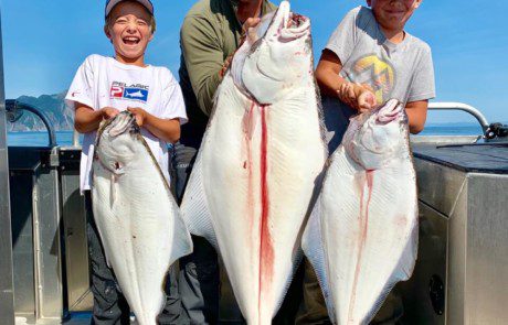 group-angler-child-posing-halibut-fish-boat-2022-3-17 An angler and two children showing off the three large halibut they caught.