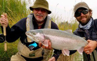 group-angler-posing-rainbow-trout-fish-bank-2022-3-17 Two anglers posing with a large rainbow trout they caught