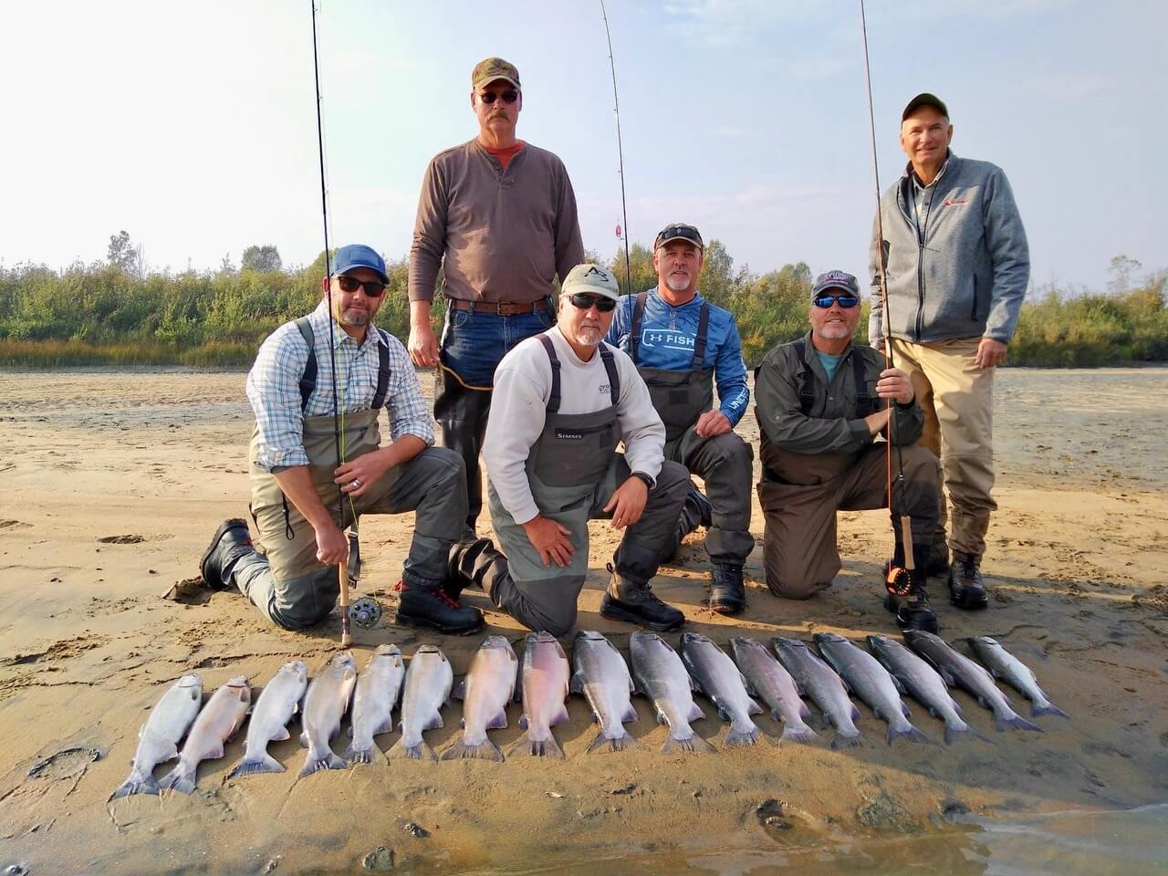 A group of anglers on the shore posing with their catch of sockeye salmon.