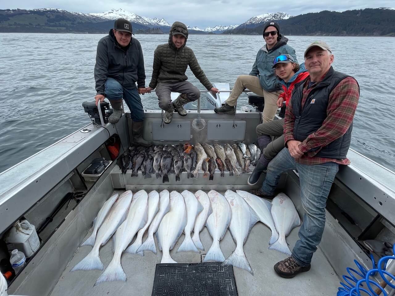 group-angler-posing-varied-fish-boat-2022-3-17 A group of anglers displaying their sizable catch while offshore fishing.