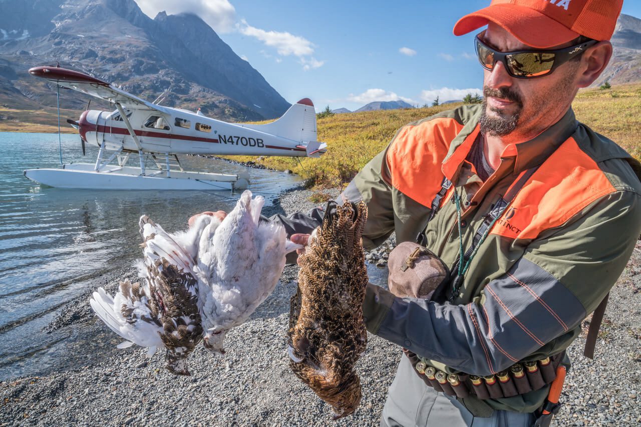 A hunter displaying a couple of ptarmigan grouse.